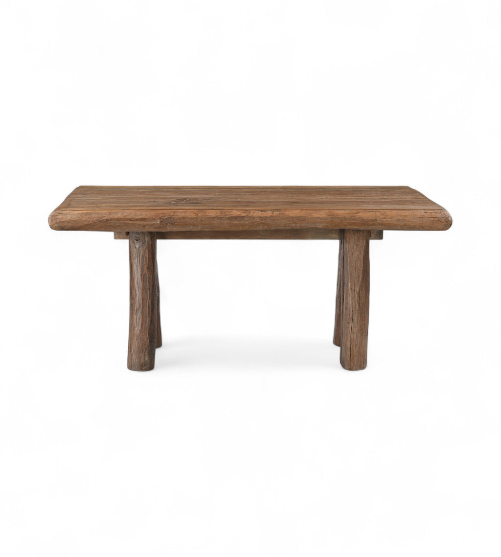 A rectangular kitchen dining table made of old solid reclaimed wood with thick cylindrical legs.