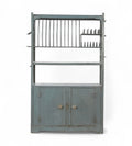 Vintage iron kitchen rack with blue-grey paint patina, featuring plate slots, cup hooks, and a lower cabinet.