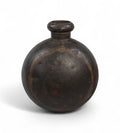 A vintage solid iron pot with a round shape and a visible natural patina, used historically for storing water or oil, now serving as a decorative vase.
