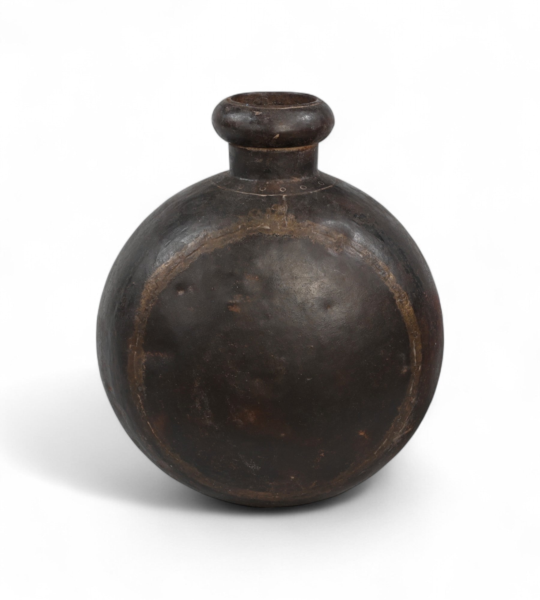 A vintage solid iron pot with a round shape and a visible natural patina, used historically for storing water or oil, now serving as a decorative vase.