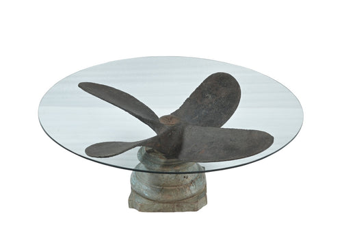 Glass table with a metal propeller design on a white background