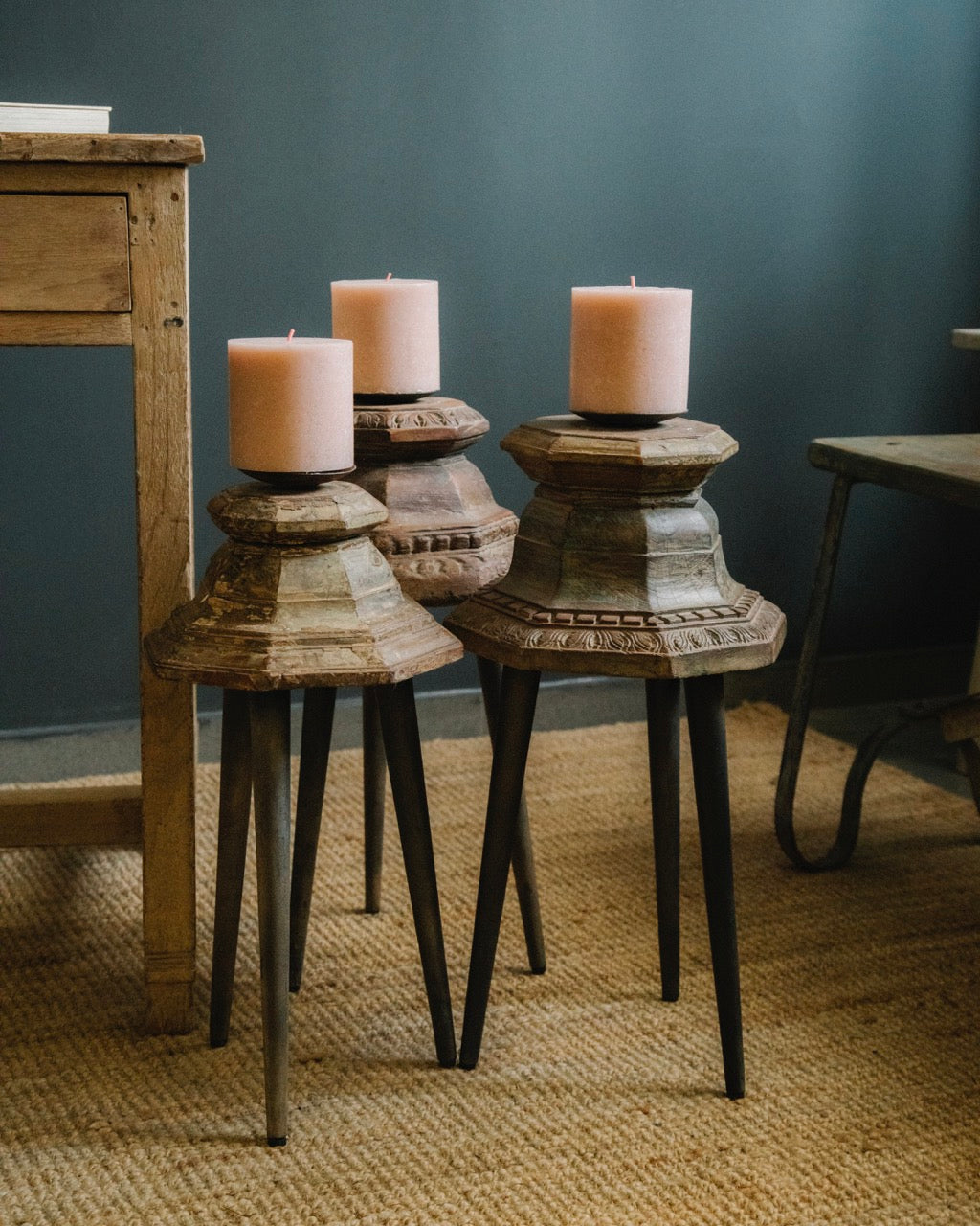 Decorative candle holders with candles on a textured surface against a dark wall.