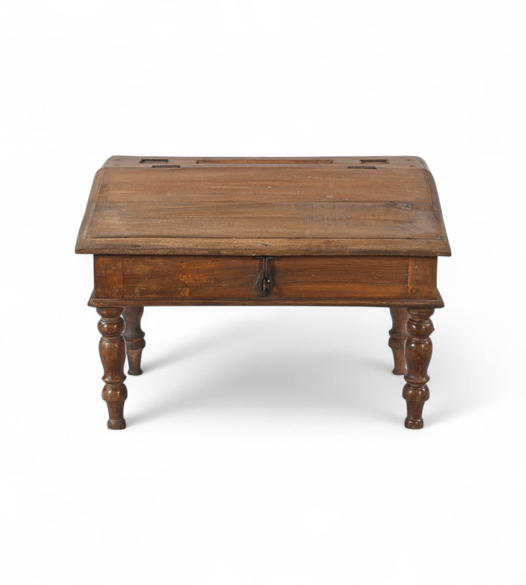 A vintage teak wood desk with a visible wood grain pattern and carved legs, with a closed hinged lid.