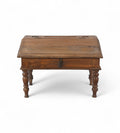 A vintage teak wood desk with a visible wood grain pattern and carved legs, with a closed hinged lid.