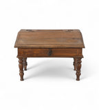 A vintage teak wood desk with a visible wood grain pattern and carved legs, with a closed hinged lid.