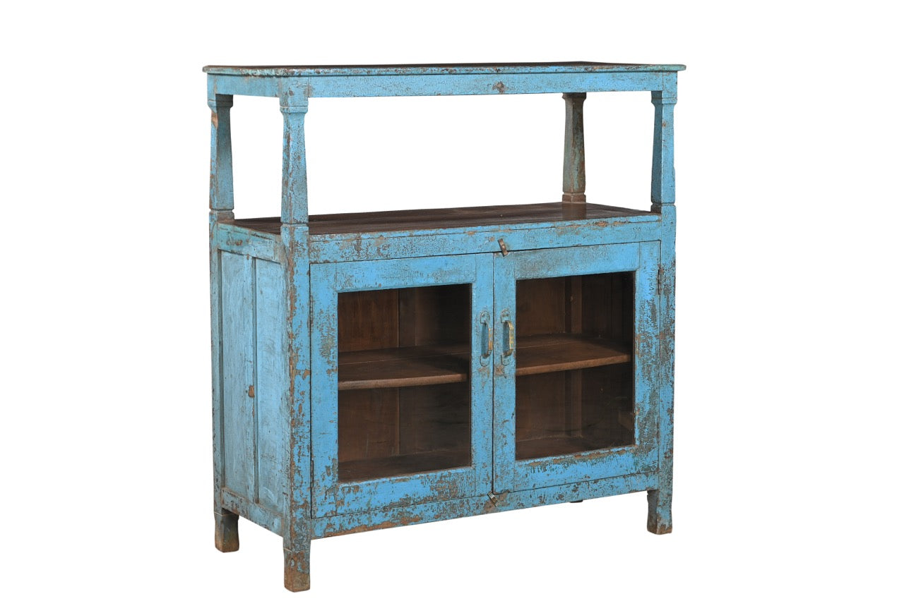 A vintage teak wood and glass cabinet with blue paint and patina, featuring a top shelf and double doors.