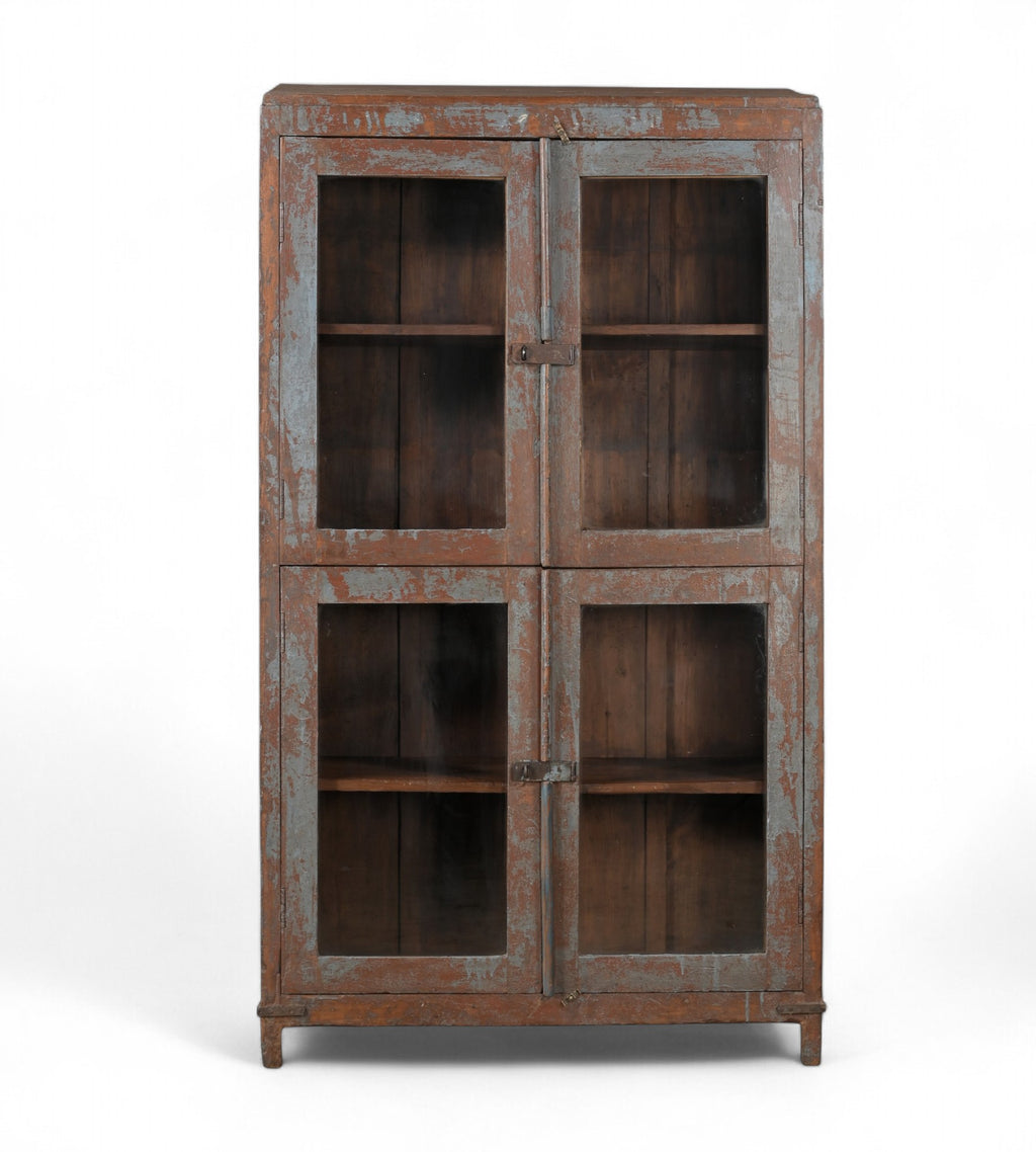 A vintage teak wood glass display cabinet with four glass doors and a visible wood patina of earthy brown and faded indigo.