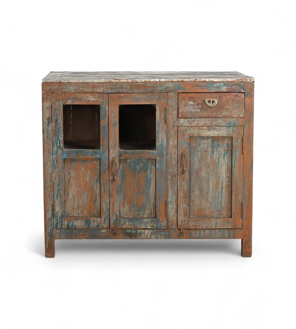 A vintage teak wood cabinet with glass panels on the doors and a painted terracotta red, deep blue, and neutral colours finish.