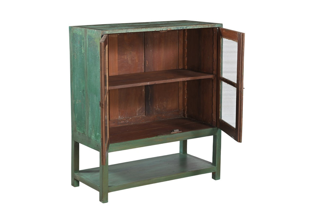 A vintage teak wood glass display cabinet with green paint on the exterior and brown interior, featuring two glass panelled doors with a single shelf.