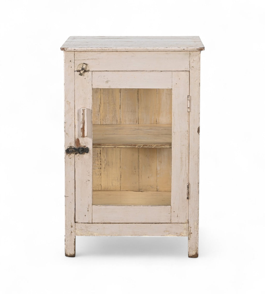 A vintage teak wood side cabinet in a white finish with a glass panel on the door, and one internal shelf.
