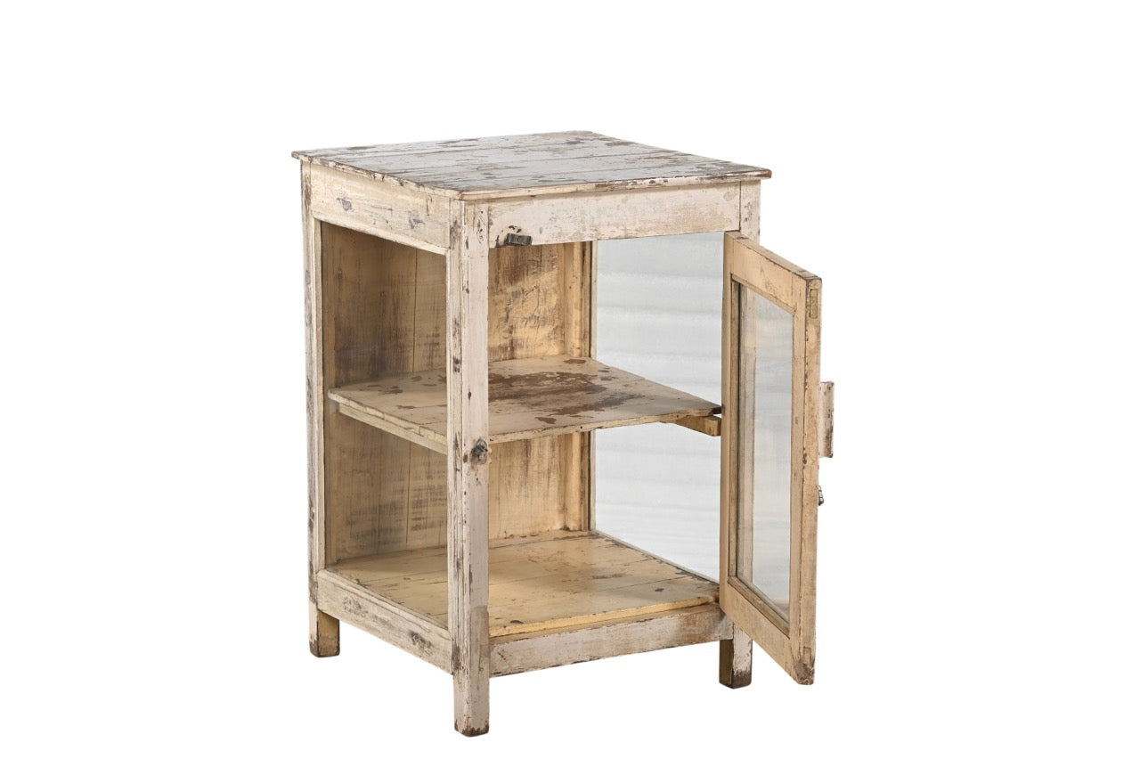 A vintage teak wood side cabinet in a white finish with a glass panel on the door, and one internal shelf.