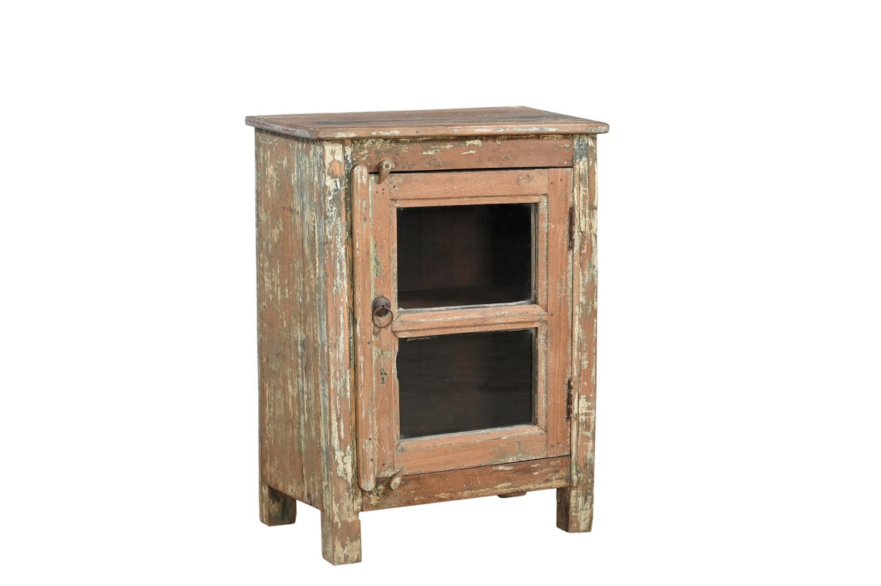 A vintage teak wood side cabinet with a weathered frame, a glass door, and a metal pull ring.