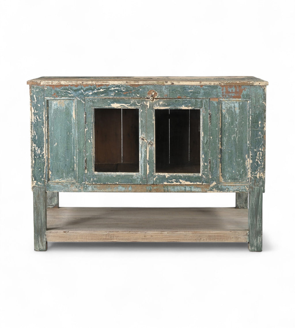 A vintage teak wood sideboard cabinet with glass double front doors and a distressed sea green finish.