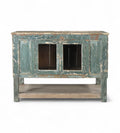 A vintage teak wood sideboard cabinet with glass double front doors and a distressed sea green finish.