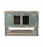 A vintage teak wood sideboard cabinet with glass double front doors and a distressed sea green finish.