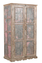 A vintage teak wood wardrobe with iron panels, featuring a carved base and an aged patina finish in soft pink and faded grey.