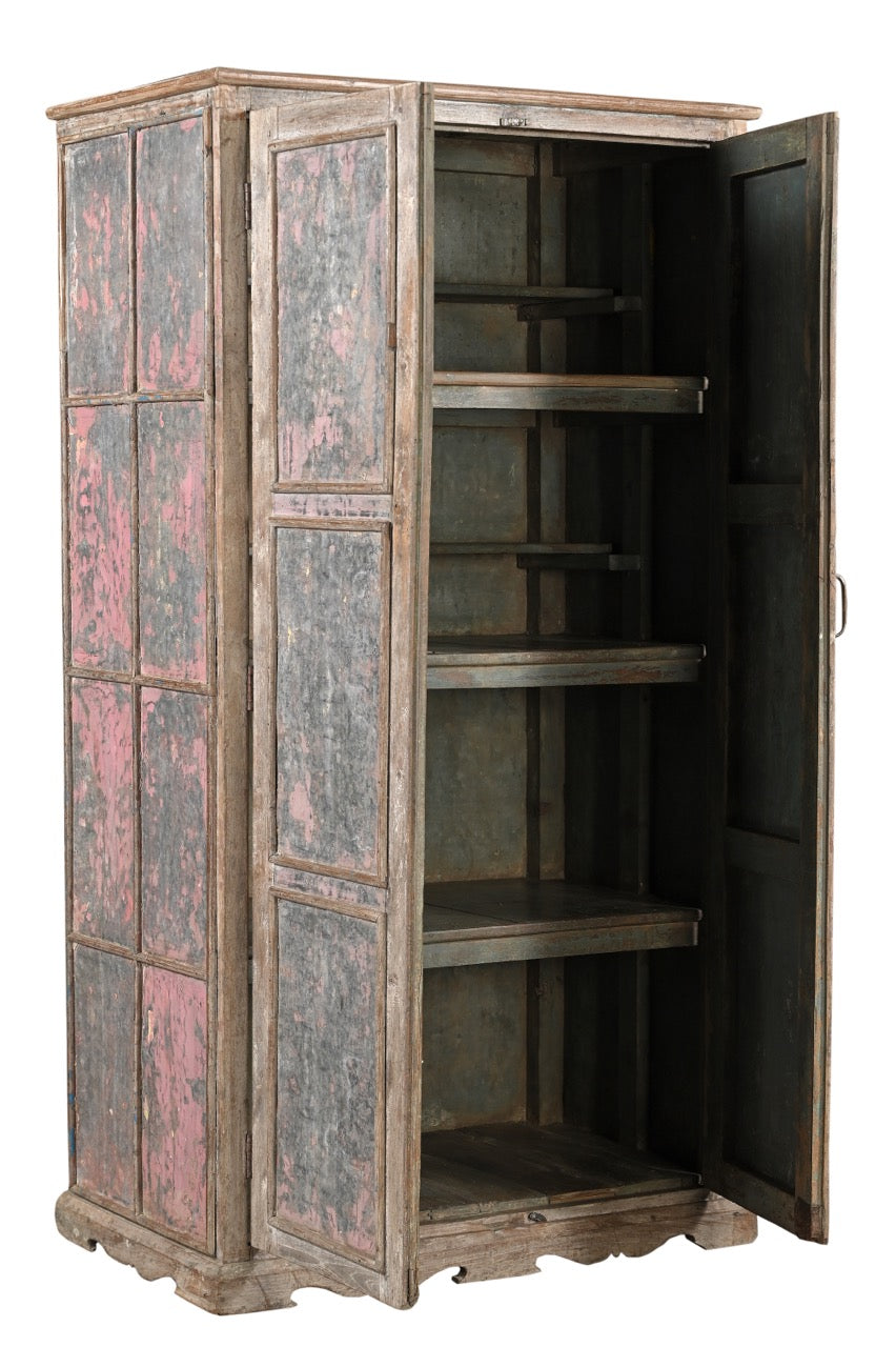 A vintage teak wood wardrobe with iron panels, featuring a carved base and an aged patina finish in soft pink and faded grey.