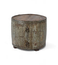 A cylindrical vintage side table made of aged iron with a teak wood top, featuring ring handles and a weathered finish.