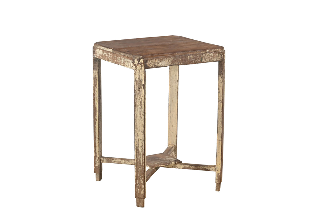 A vintage teak wood side table with visible natural grain and patina, with a cream coloured paint on the legs.
