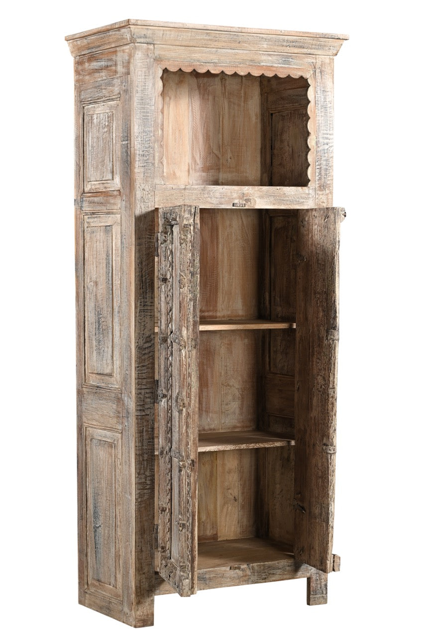 A vintage teak and recycled wood wardrobe with hand-carved details and a lime/multi-coloured patina. It features an upper open section with a scalloped wooden arch and two doors with a visible handle.