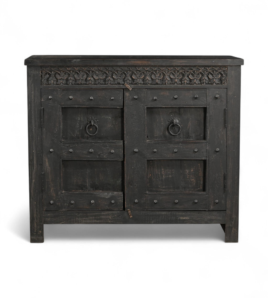 A vintage teak wood side cabinet with iron accents and a carved floral frieze, finished in black.