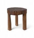 A vintage Indian teak wood stool with an irregular shape and a dark patina, indicating age and use.