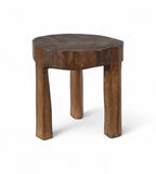 A vintage Indian teak wood stool with an irregular shape and a dark patina, indicating age and use.