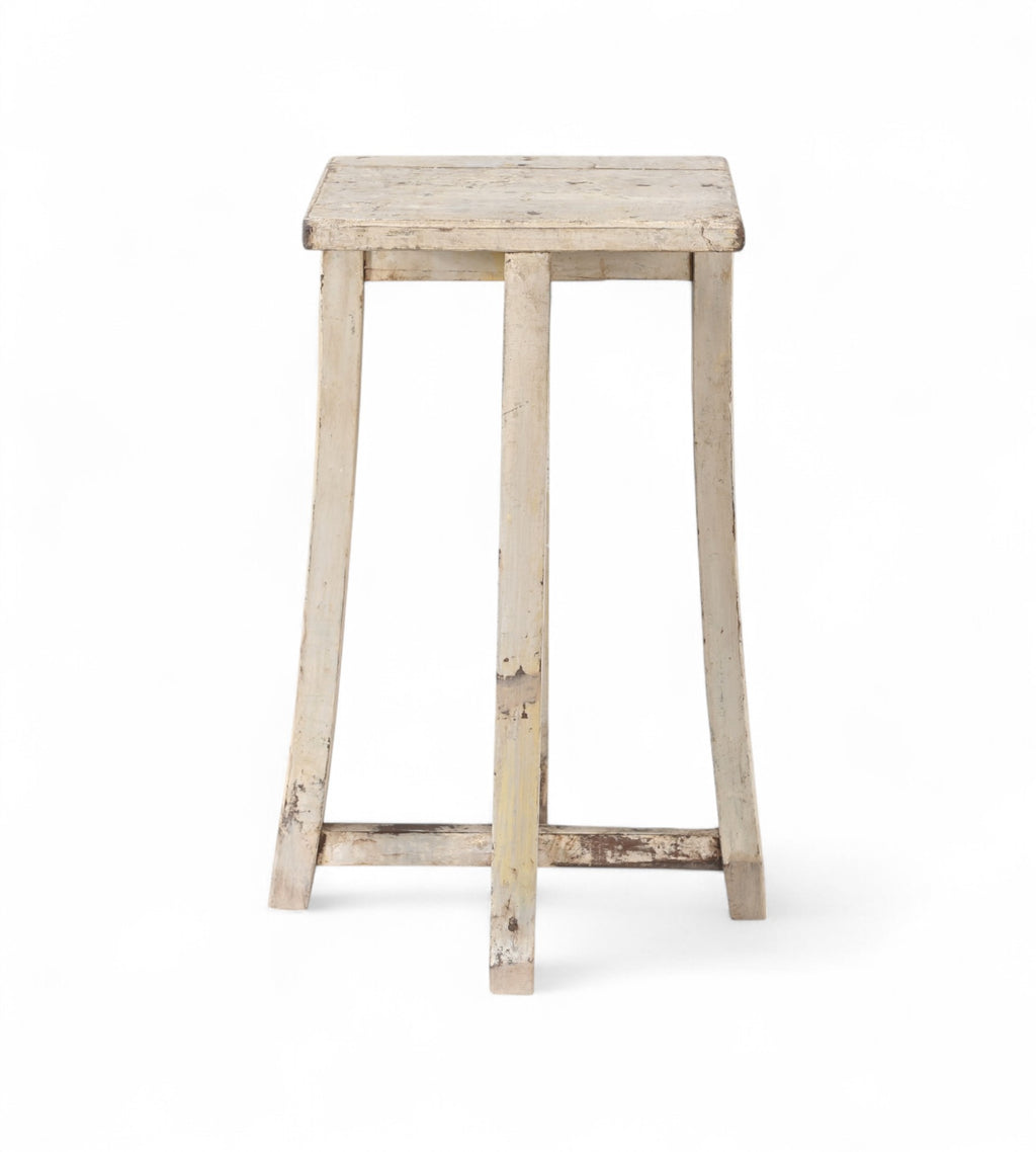 A vintage teak wood side table with subtly curved legs and a cross stretcher base, with a creamy white finish.