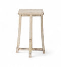 A vintage teak wood side table with subtly curved legs and a cross stretcher base, with a creamy white finish.