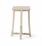 A vintage teak wood side table with subtly curved legs and a cross stretcher base, with a creamy white finish.