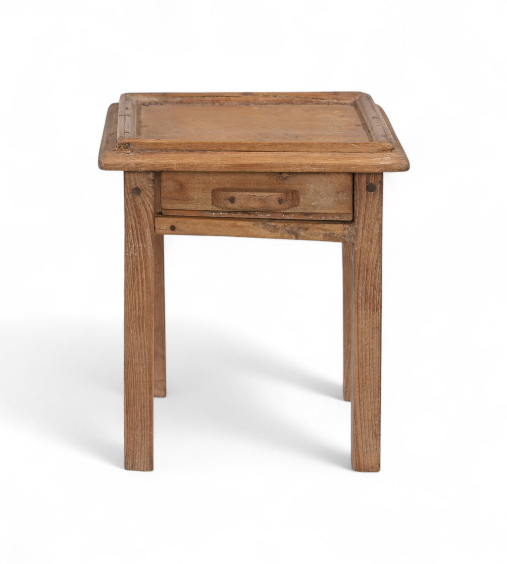 A tiny vintage teak wood side table with a visible drawer, having a natural wood finish and a metal pull ring.