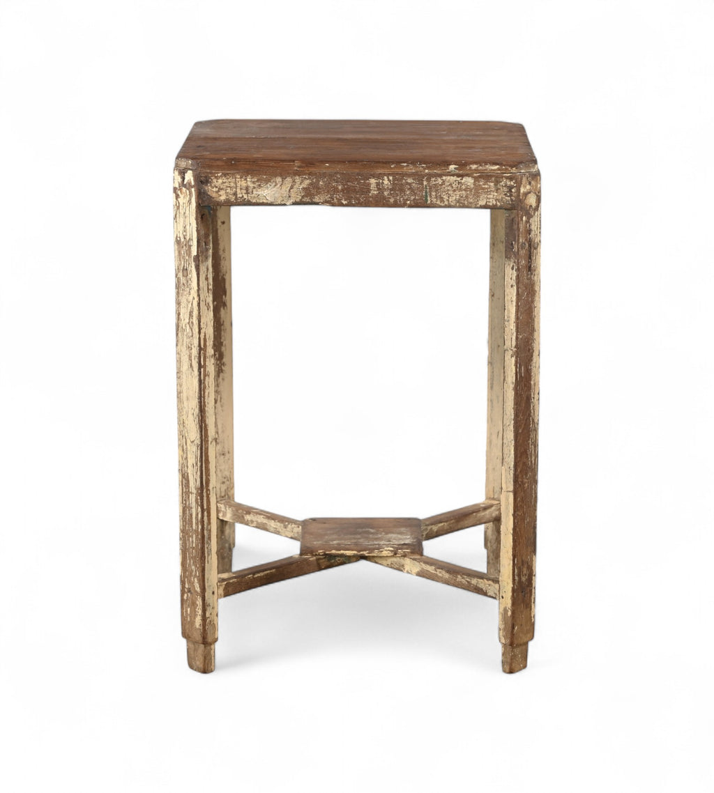 A vintage teak wood side table with visible natural grain and patina, with a cream coloured paint on the legs.