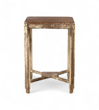 A vintage teak wood side table with visible natural grain and patina, with a cream coloured paint on the legs.