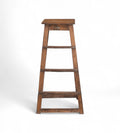 A tall vintage teak wood bar stool with a natural patina and warm tones, featuring visible wood grain and imperfections.