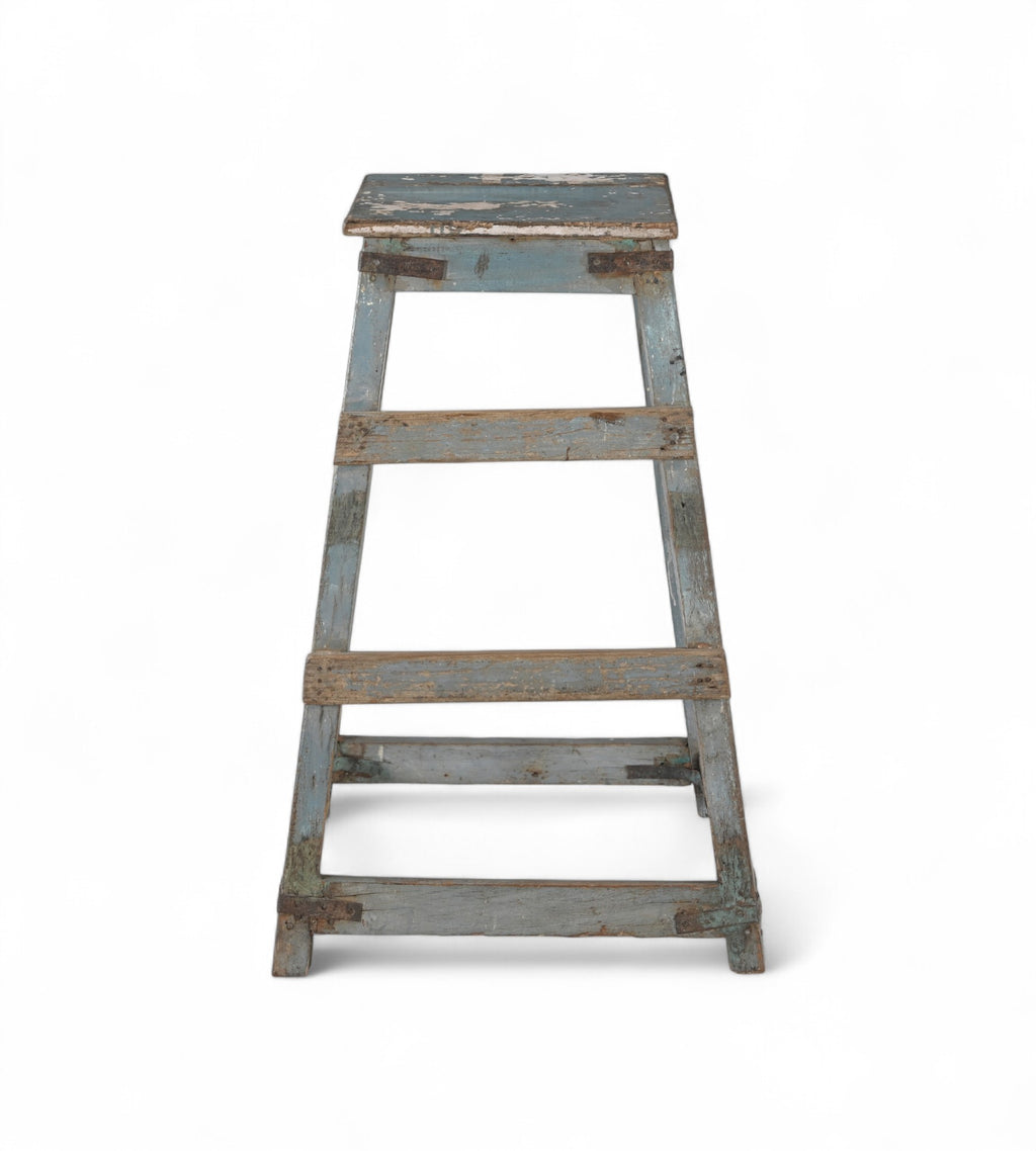 A vintage teak wood bar stool with a faded soft blue patina and iron brackets.