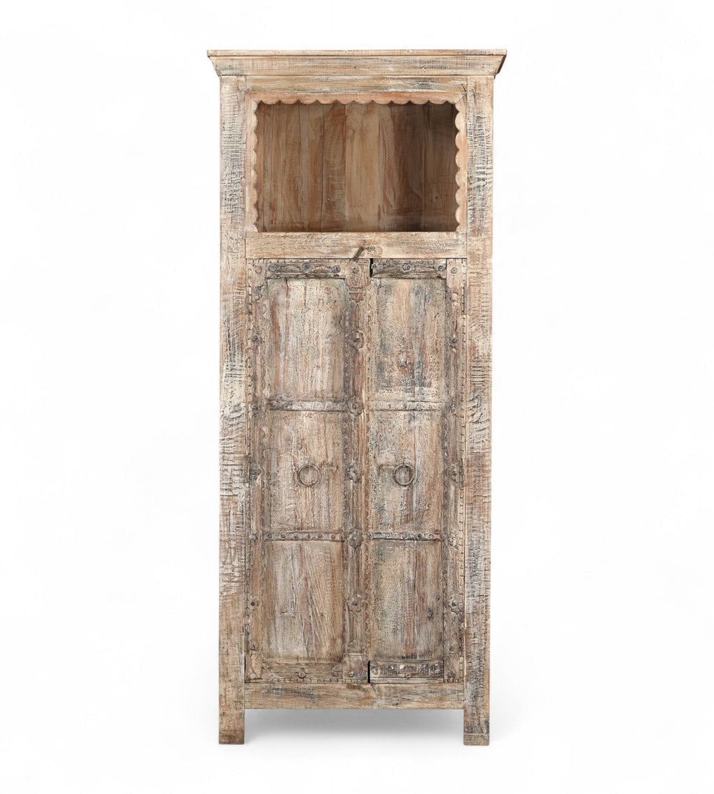 A vintage teak and recycled wood wardrobe with hand-carved details and a lime/multi-coloured patina. It features an upper open section with a scalloped wooden arch and two doors with a visible handle.