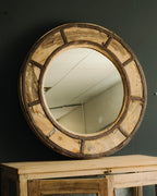 Round wooden mirror with metal accents on a dark wall