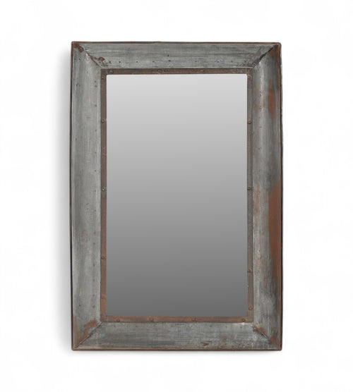 A rectangular mirror with a weathered iron frame featuring riveted detailing and a smoky patina.