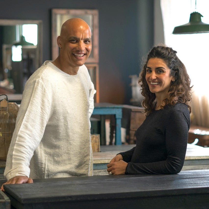 Two people standing behind a counter in a rustic interior setting