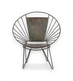 An iron chair with a fan back design and rounded profile, featuring slender legs and a cushioned seat.