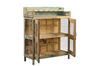 A vintage reclaimed wood glass cabinet with aged paint in soft yellows, weathered green, and turquoise, featuring glass panelled doors and a built-in shelf.