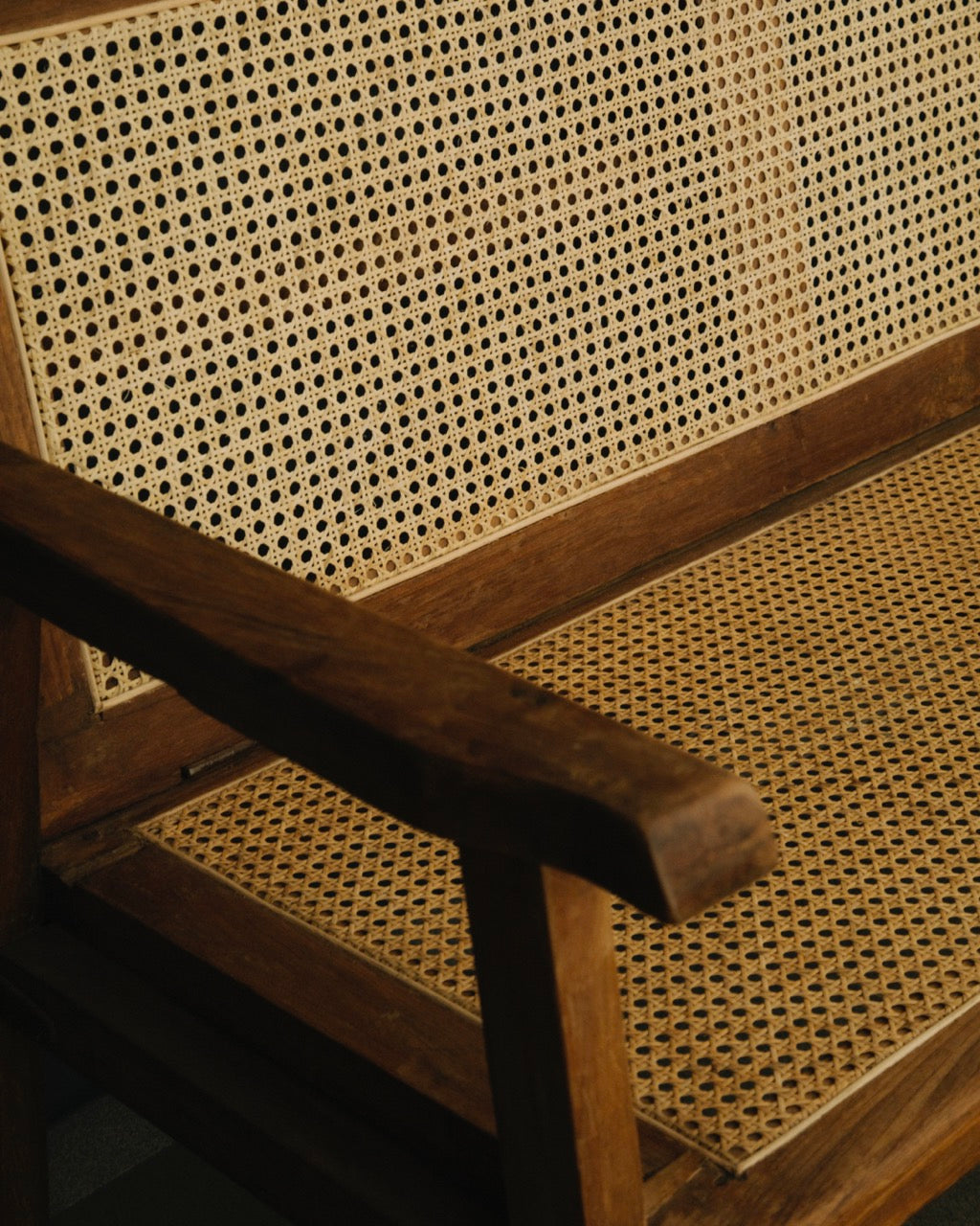 Close-up of a wooden chair with woven cane seat and backrest.