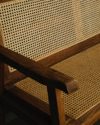 Close-up of a wooden chair with woven cane seat and backrest.