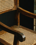 Close-up of a wooden chair with wicker seat and backrest against a dark background
