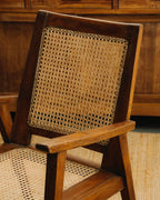 Wooden chair with wicker seat and backrest against a wooden panel background